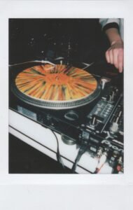 Hand on a black turntable spinning a vinyl record
