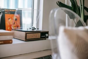 Vintage record player on a windowsill beside a stack of vinyl records